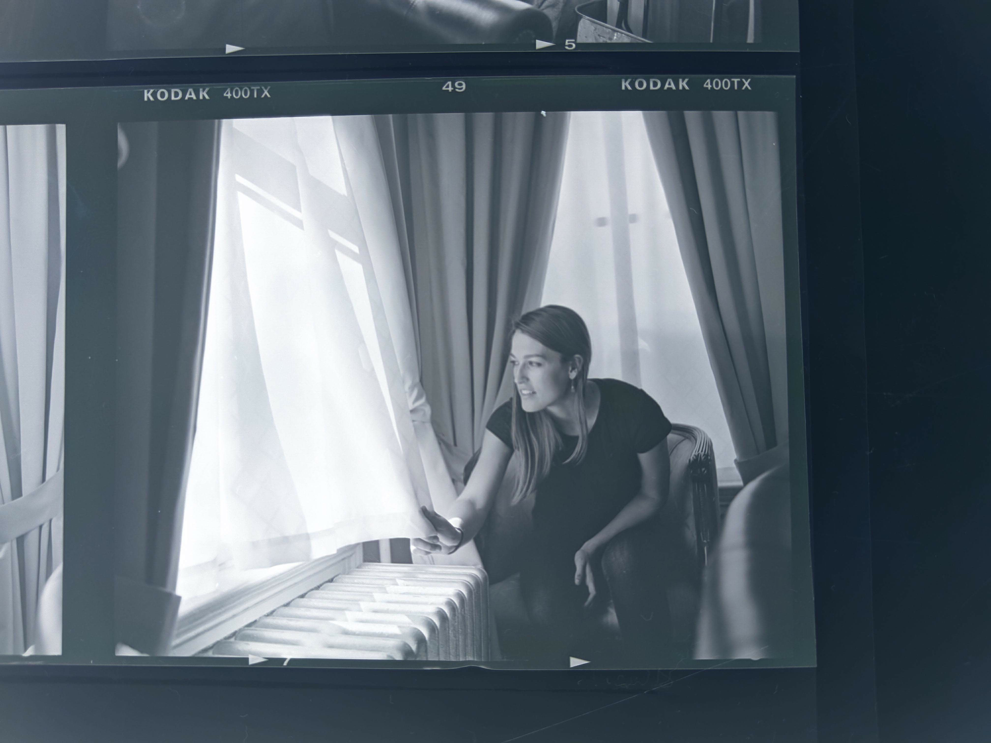 black & white image of olivia sitting in a chair, looking out the window